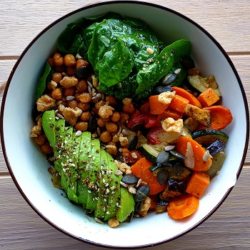 a bowl with bulgur, lentils, chickpeas, avocado, spinach and roasted vegetables.